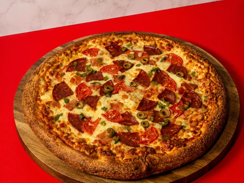 A pepperoni and green olive pizza on a wooden board