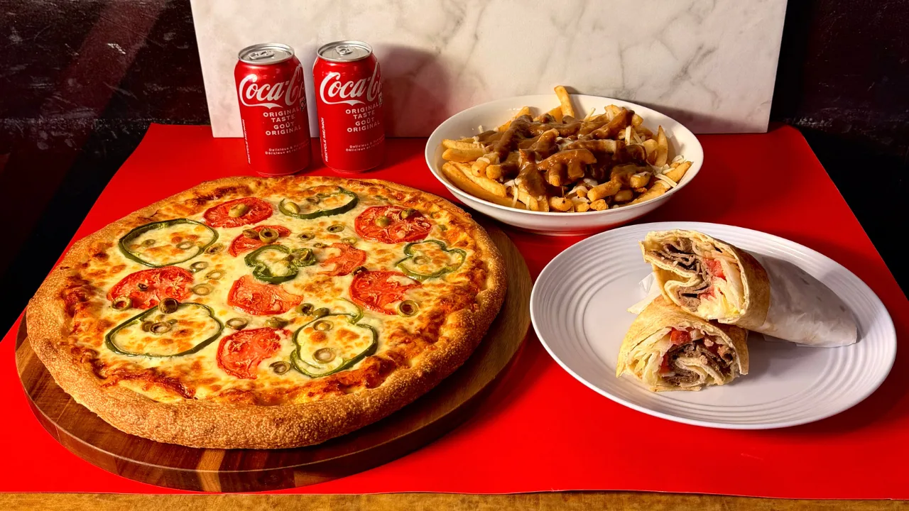 A Season's Pizza spread: a thick-crust pizza with tomatoes and green peppers, a bowl of poutine, a donair wrap and two cans of Coca-Cola